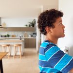 boy changing temperature on central thermostat