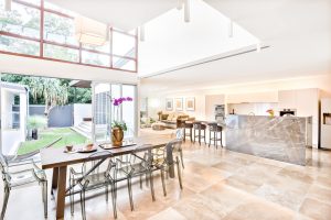 A large dining area, kitchen and living room looking out onto a garden