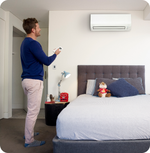 man in bedroom controlling his split system airconditioner with a remote