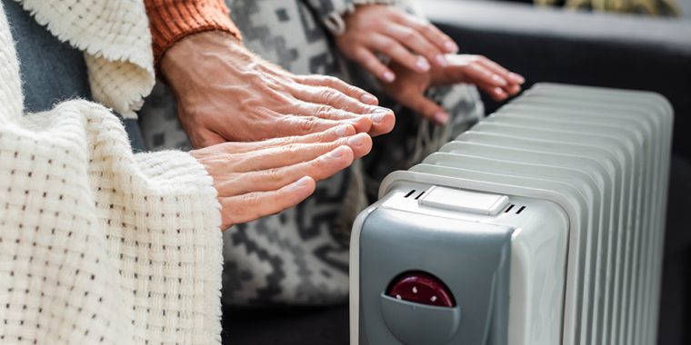 People warming their hands near a free standing portable heater